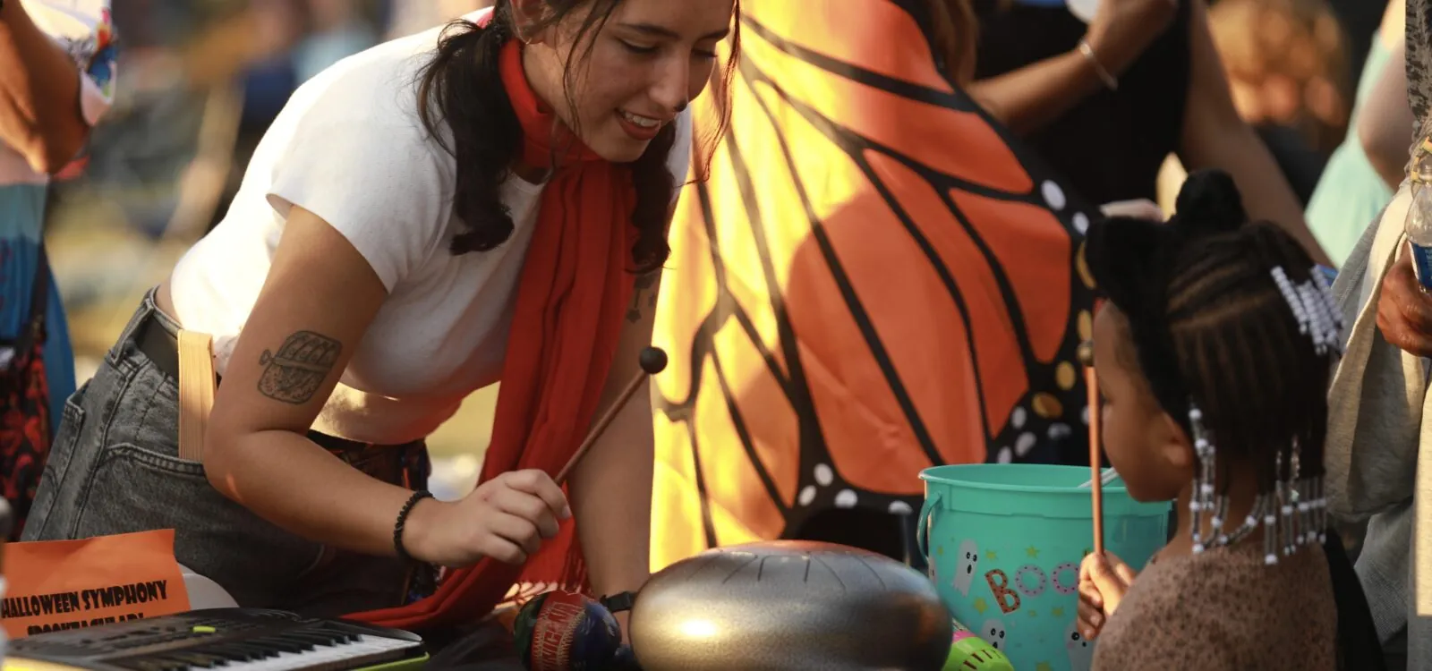 Student playing a drum with a child at a community event.