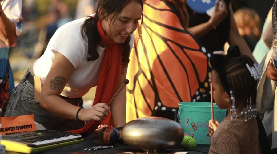 Student playing a drum with a child at a community event.