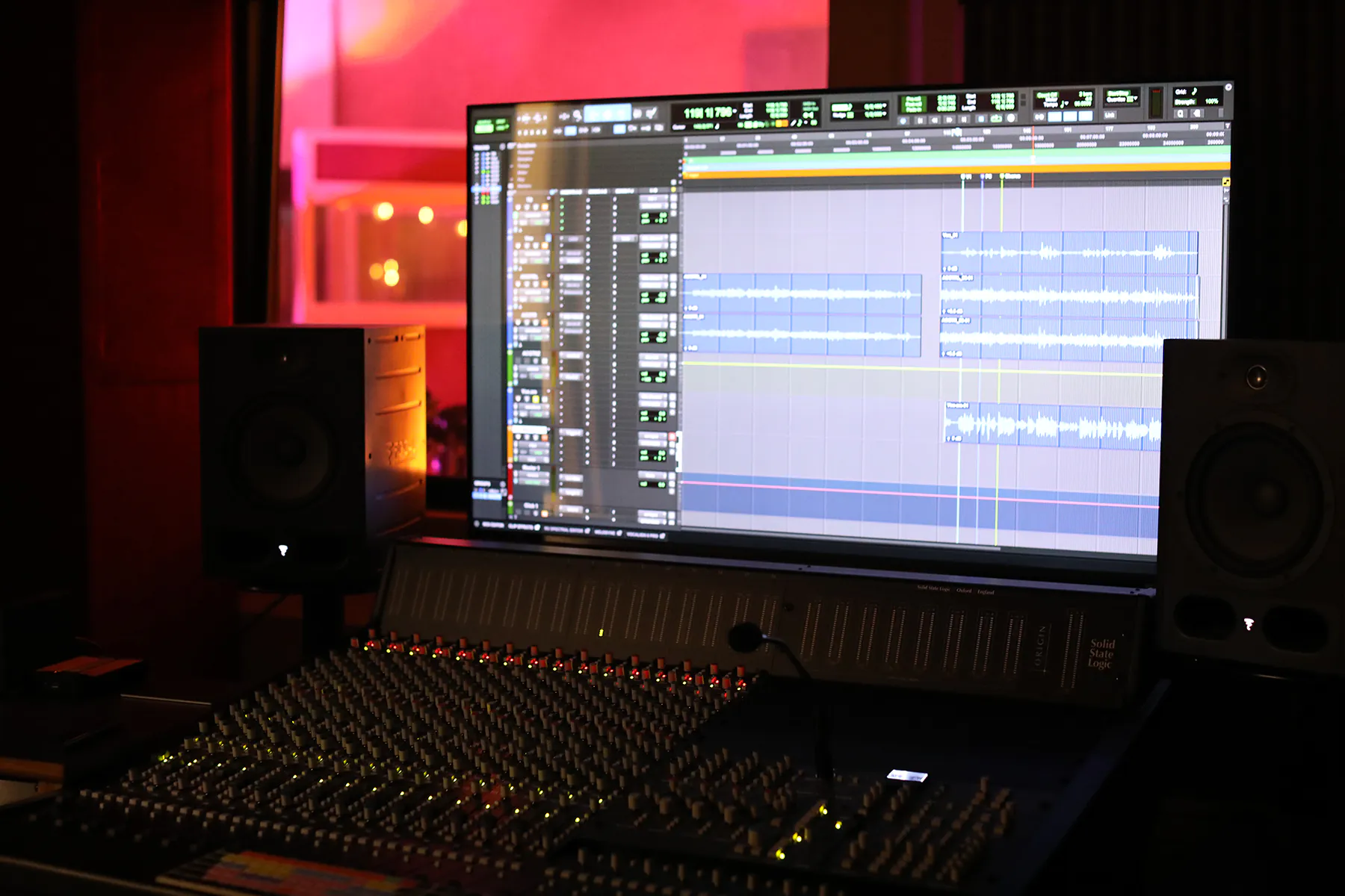 Computer screen showing recording software with recording studio in background.