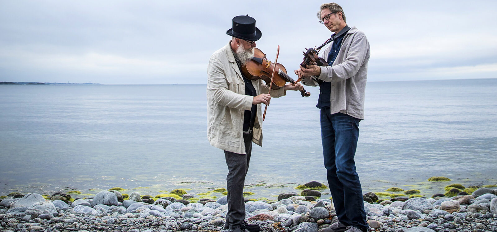 2 men with instruments standing on rocky beach