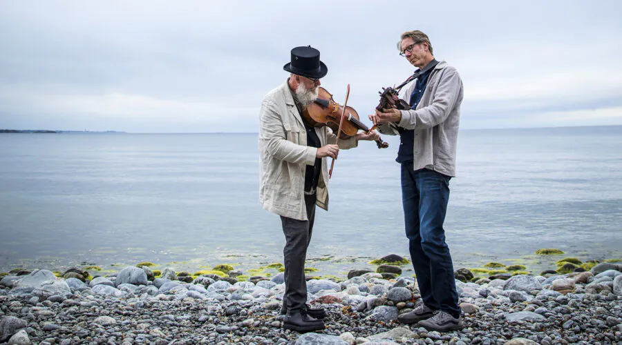2 men with instruments standing on rocky beach