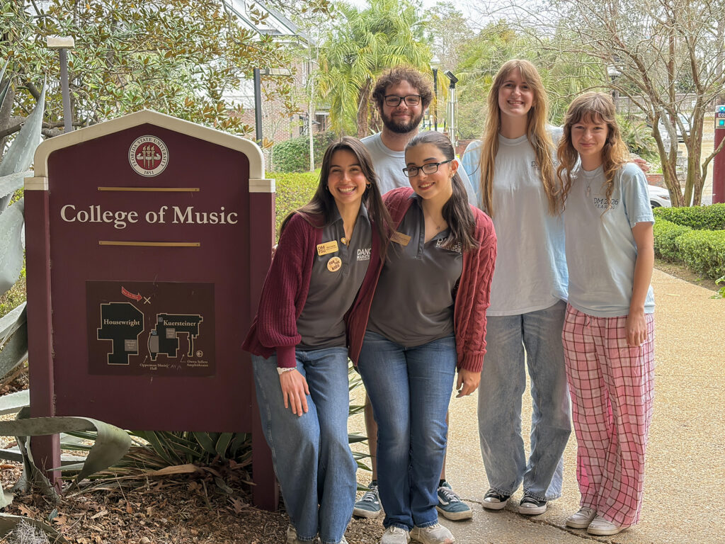 Five students standing by College of Music sign