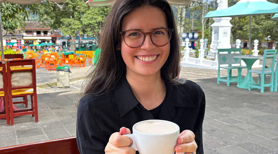 Smiling young woman holding coffee cup at an outdoor cafe