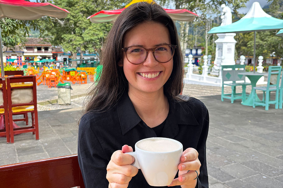 Smiling young woman holding coffee cup at an outdoor cafe