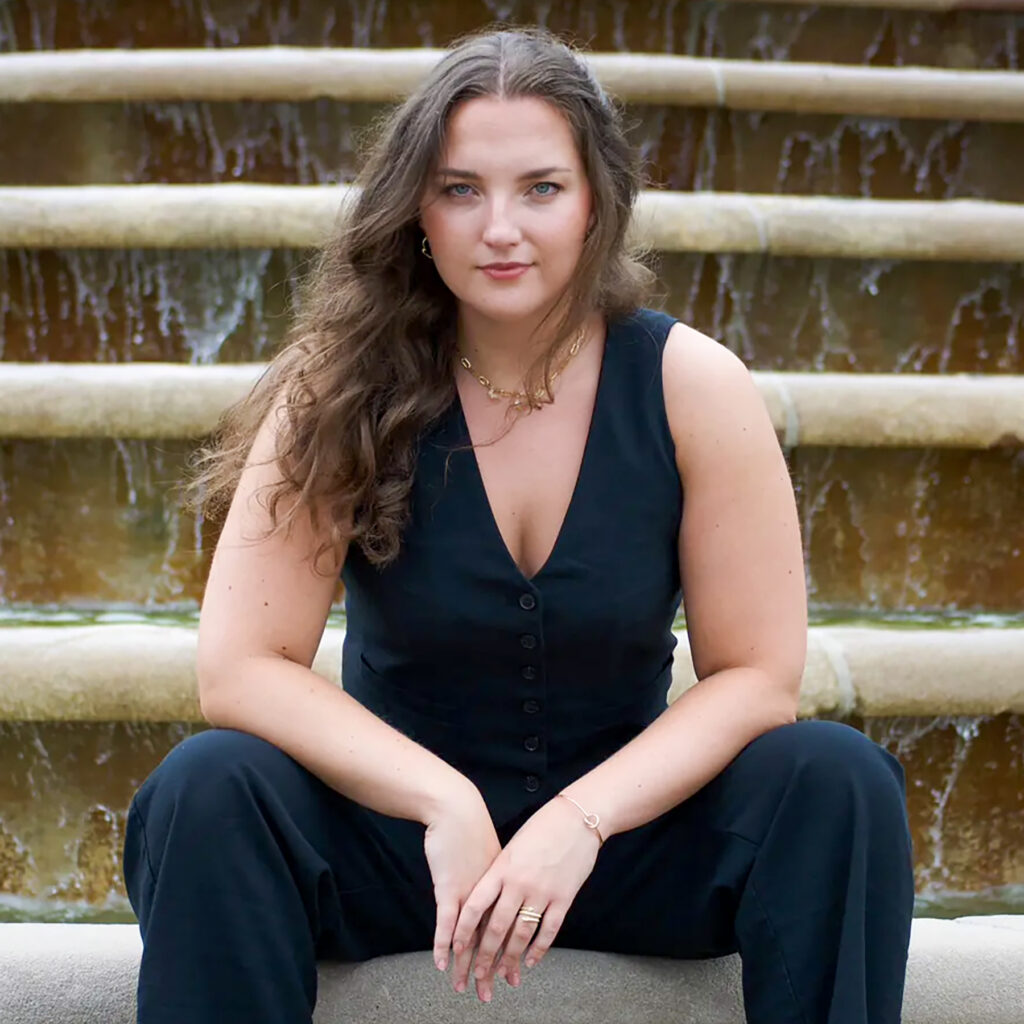 Young woman seated on edge of fountain