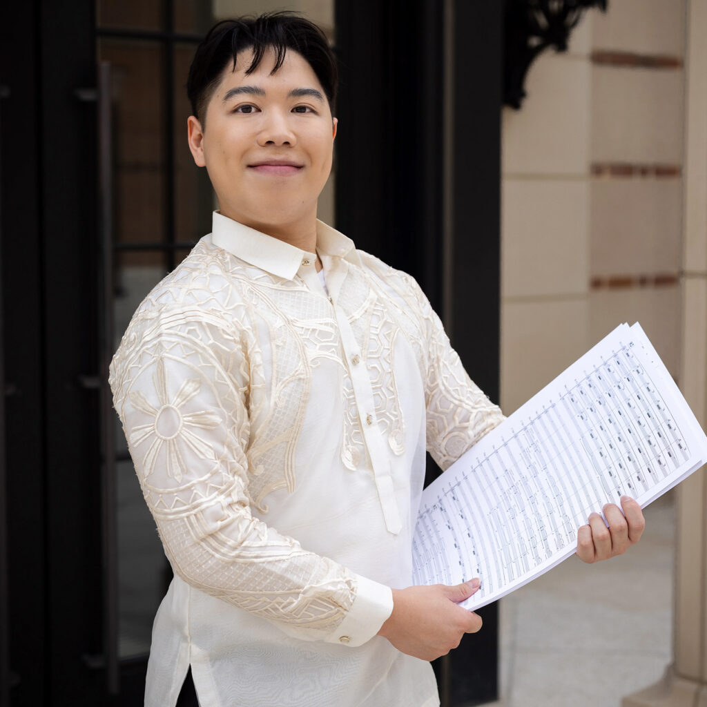 Photo of smiling young man holding music score