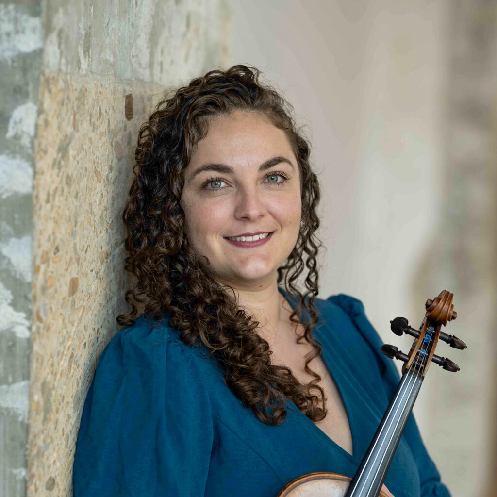 Headshot of smiling young woman holding violin