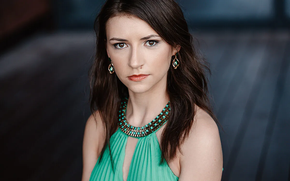 Petite young woman with dark hair staring intently at camera