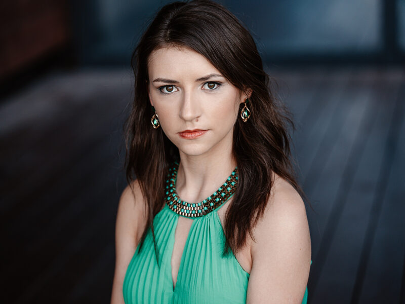 Petite young woman with dark hair staring intently at camera