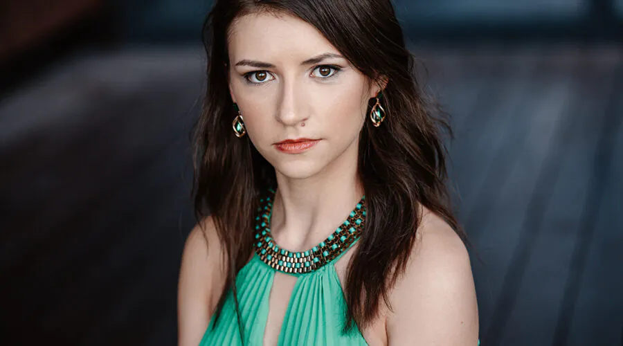 Petite young woman with dark hair staring intently at camera