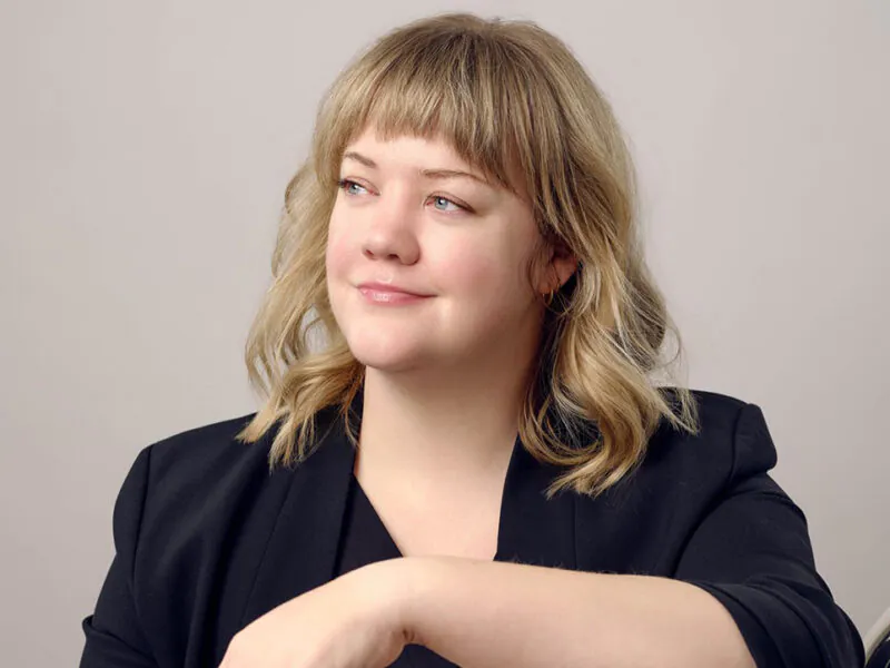3/4 profile of smiling young woman against muted backdrop