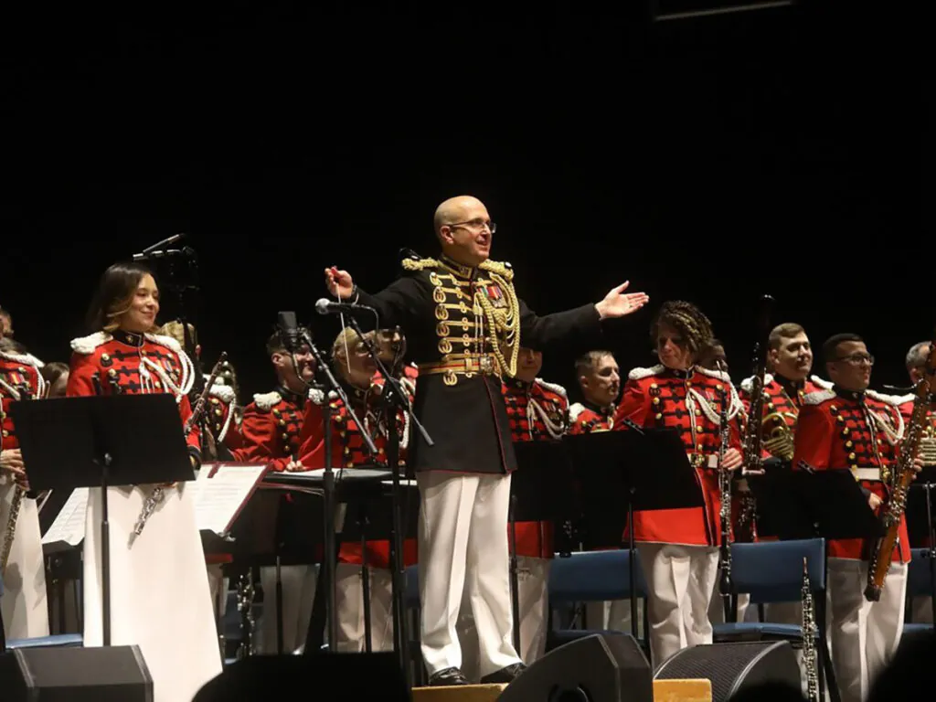 Conductor standing with military band on stage