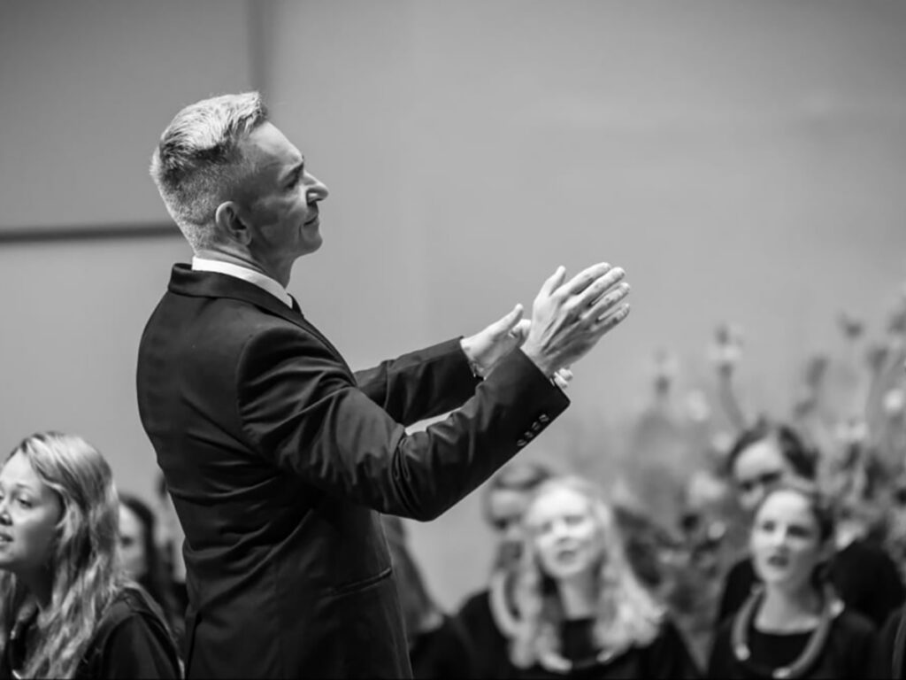 Black and white photo of man conducting choir