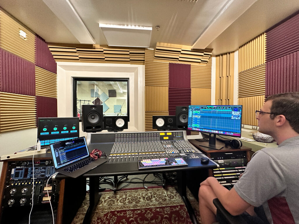 Young man seated in front of recording equipment