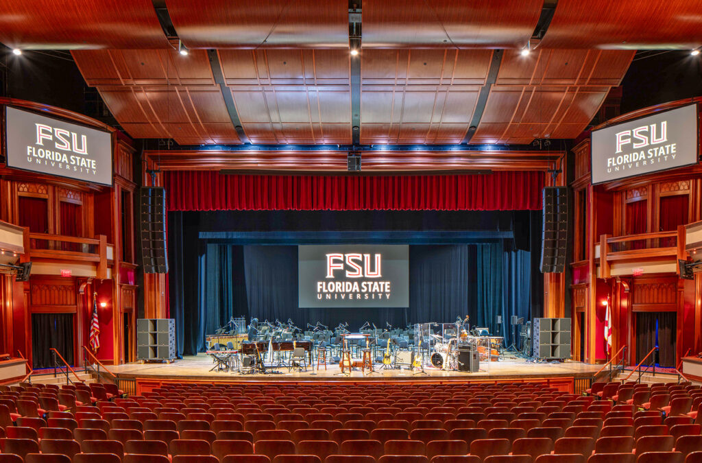 Fully lit empty performance hall with stage set up for performance