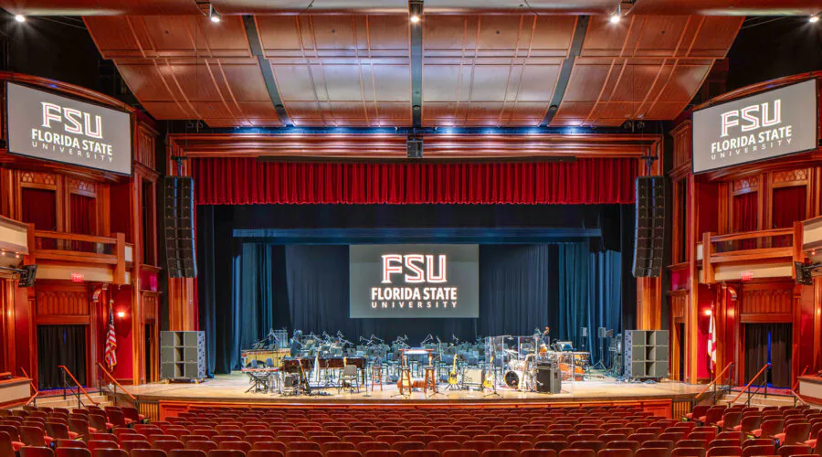 Fully lit empty performance hall with stage set up for performance