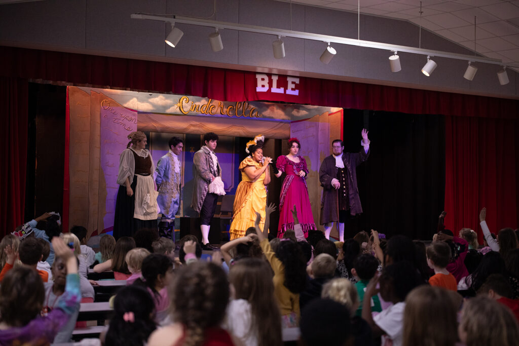 Six young musicians in costume on stage at an elementary school