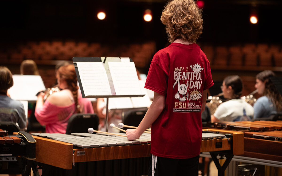Young percussionist seen from behind during band rehearsal on stage