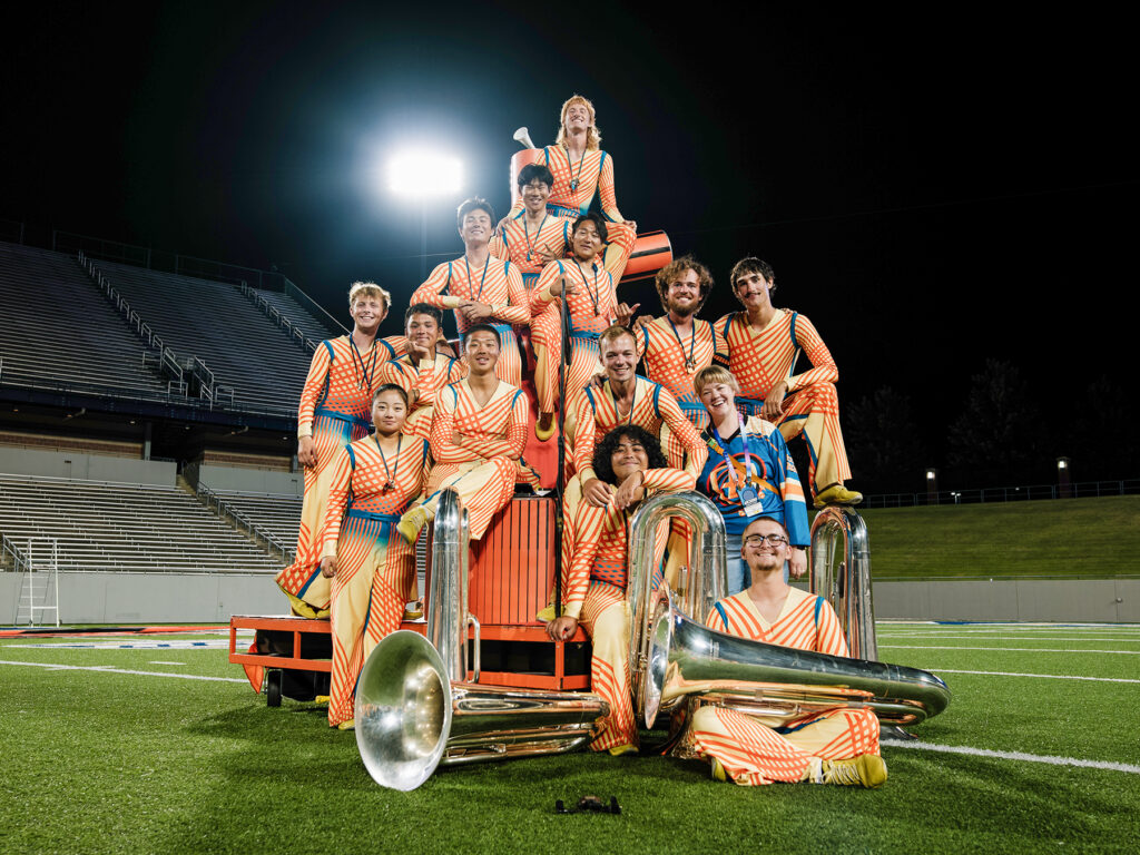 Young men posing with brass instruments on football field