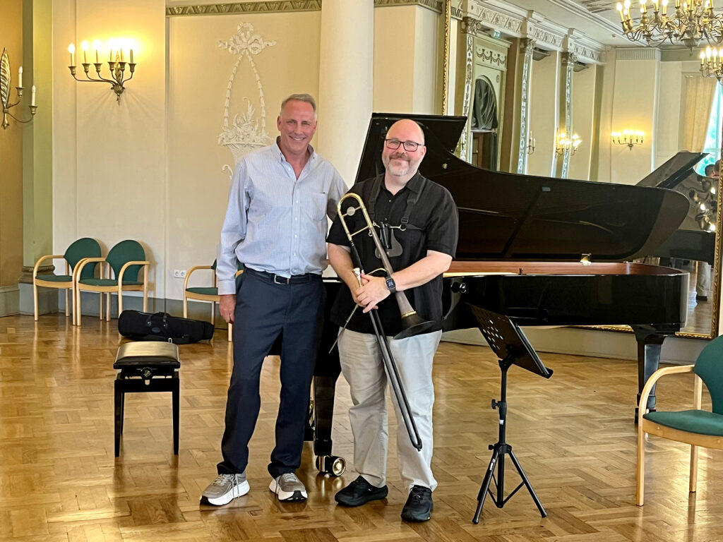 Two men standing near piano in ornate hall