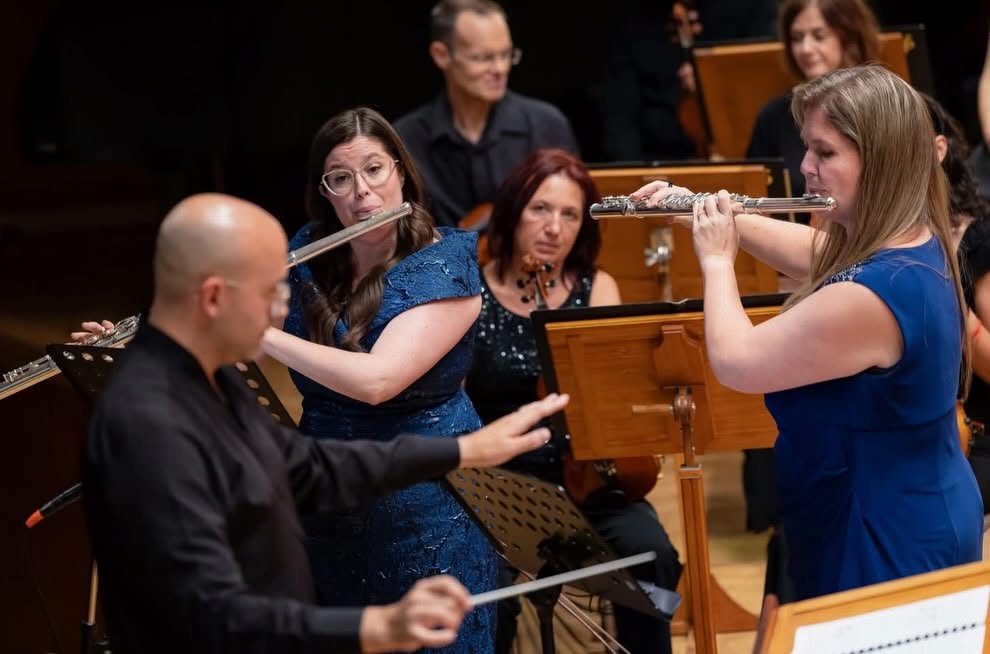 Two flute soloists on stage near conductor during an orchestral concert