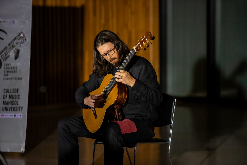 Man with long dark hair playing guitar on stage