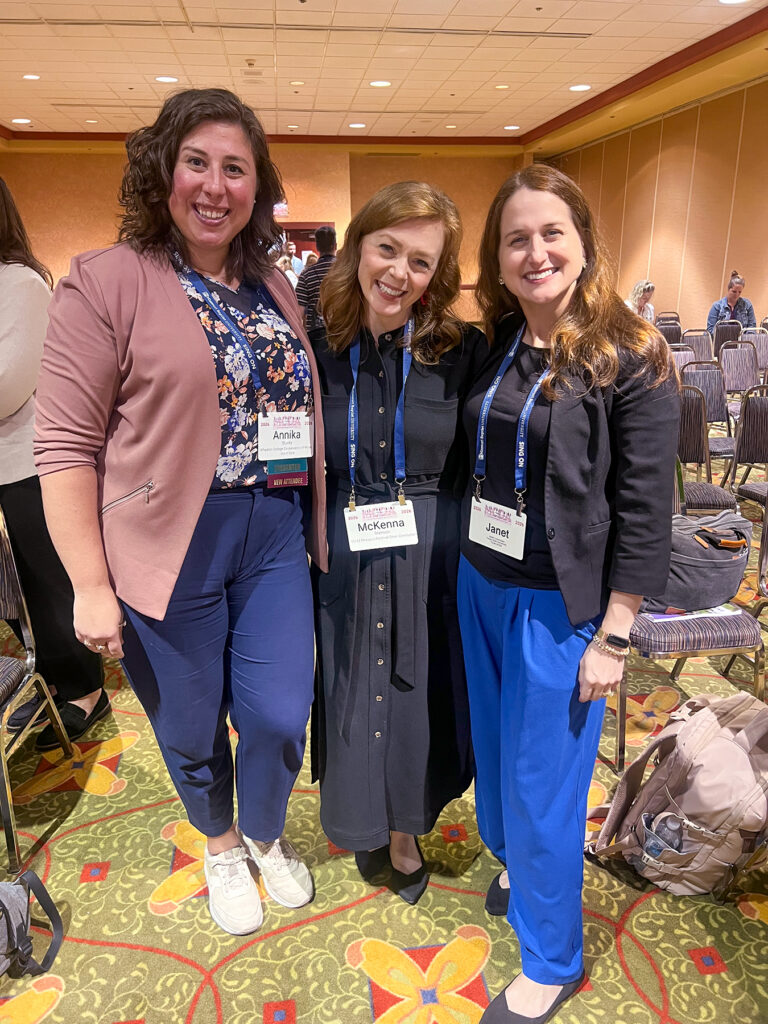 three women at a conference smiling for photo