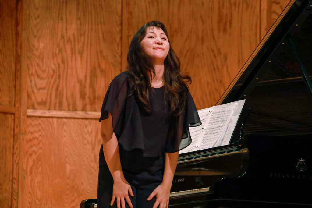 Young woman smiling on stage near piano