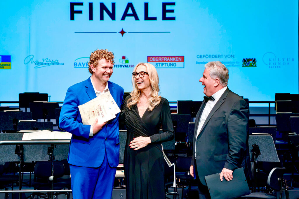 Three smiling individuals on stage
