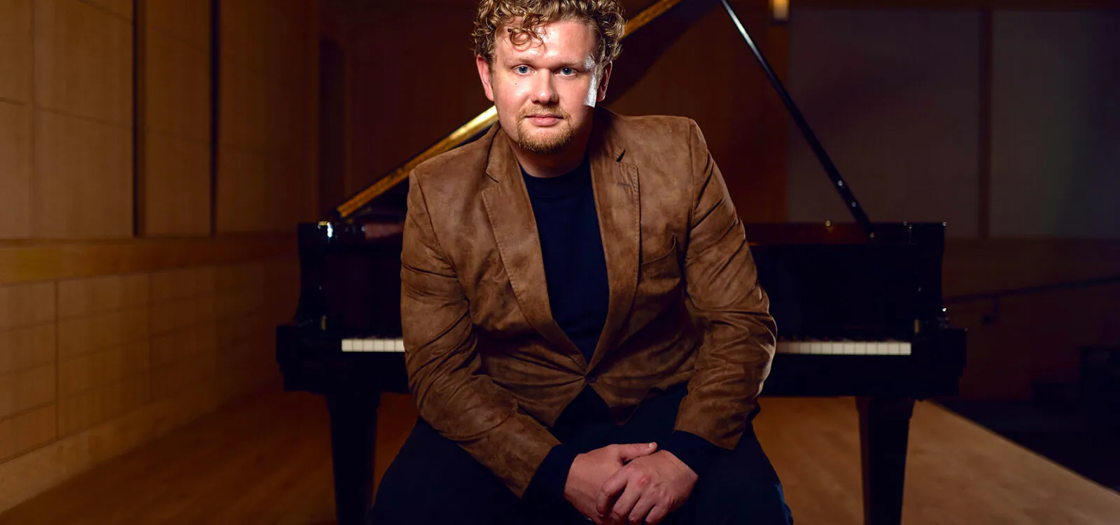 Young man sitting on piano bench with back to piano