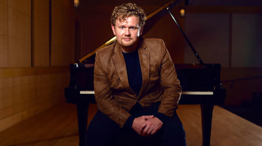 Young man sitting on piano bench with back to piano